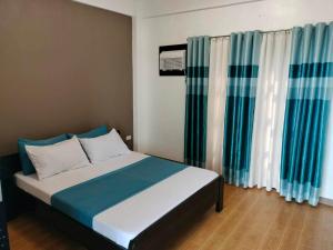 a bed in a room with blue and white curtains at casita de flocerfida in Boac