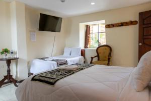 a hotel room with two beds and a flat screen tv at Back Packer in Ibarra