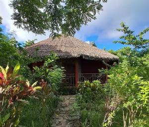 a small hut with a thatched roof in a garden at Zara Village in Nosy Be