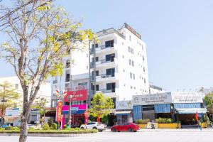 a building on a city street with a red car at Sonne Hotel Quang Binh in Dong Hoi