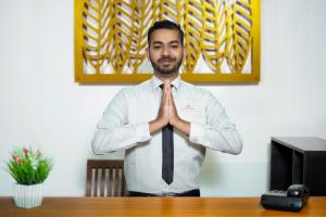 a man in a dress shirt and tie sitting at a desk at La Cottage in Nuwara Eliya