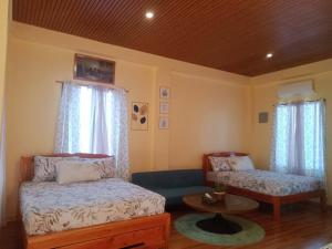 a bedroom with two beds and a table and windows at JJS BACKPACKERS VILLAGE in Siquijor +57 photos