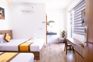 a hotel room with two beds and a desk at Sonne Hotel Quang Binh in Dong Hoi