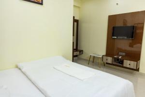 a bedroom with a white bed and a tv at SKS Residensy in Kāraikkudi