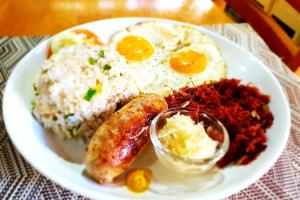 a plate of breakfast food with eggs sausage and rice at MJs Garden Hotel Moalboal powered by Cocotel in Moalboal
