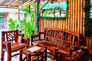two wooden benches and a table and chairs on a patio at MJs Garden Hotel Moalboal powered by Cocotel in Moalboal +10 photos