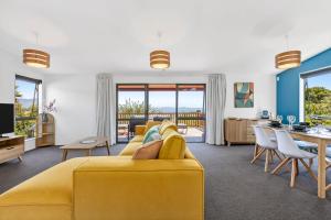 a living room with a yellow couch and a dining room at Kotare Heights in Pohara