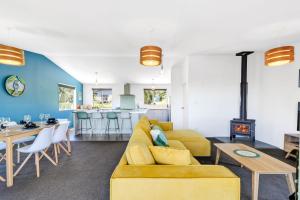 a living room with a yellow couch and a table at Kotare Heights in Pohara