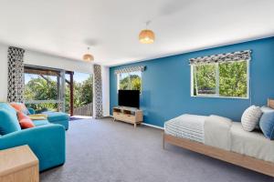 a blue bedroom with a bed and a couch at Kotare Heights in Pohara +11 photos