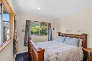 a bedroom with a bed and a window at Penguin Cottage in Tarakohe