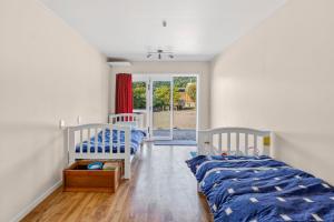 a bedroom with two beds and a sliding glass door at Penguin Cottage in Tarakohe