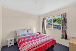a bedroom with a bed and a window at Penguin Cottage in Tarakohe
