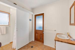 a bathroom with a sink and a wooden door at Penguin Cottage in Tarakohe