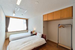 a hotel room with two beds and a window at villa Jin Asahikawa in Asahikawa