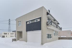 a house with a white garage door in the snow at villa Jin Asahikawa in Asahikawa