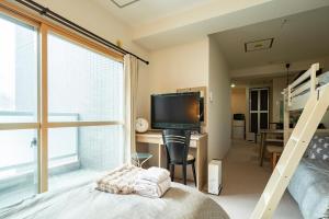 a bedroom with a bed and a desk with a television at Fewdays Condominium301 in Sapporo