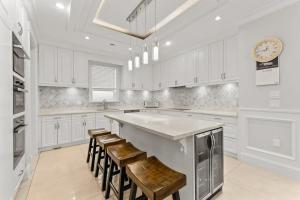 a kitchen with white cabinets and a large island with stools at 嘉博旅馆 Jiabo Hotel in Richmond +10 photos
