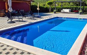 a blue swimming pool with chairs and a house at Villa Rubin with heated pool in Slivno