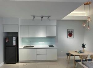 a kitchen with white cabinets and a black refrigerator at seroja hills condominium in Sepang