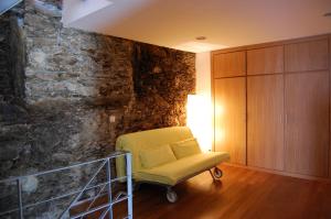 a yellow chair in a room with a stone wall at Quinta dos Castanheiros - Turismo Rural in Negreda