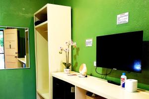 a green wall with a desk with a television on it at MJs Garden Hotel Moalboal powered by Cocotel in Moalboal
