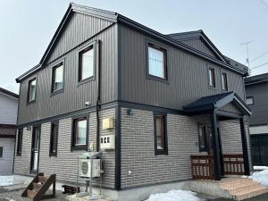 a gray house with a gambrel roof at Chalet Yutaka in Furano