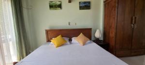 a bedroom with a bed with two yellow pillows at Villa 86 in Pamunugama