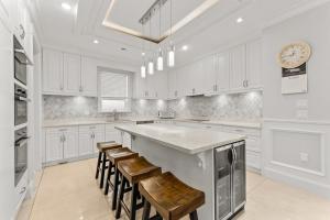 a kitchen with white cabinets and a large island with stools at 嘉博旅馆 Jiabo Hotel in Richmond