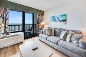a living room with a couch and a large window at Oceanfront condo Heated Pools & Breathtaking View! in Myrtle Beach