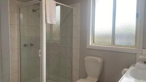 a bathroom with a shower and a toilet and a window at The Beaches on Lakes Cottage - Cosy Coastal Escape in Lakes Entrance +10 photos