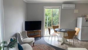 a living room with a television and a table and chairs at The Beaches on Lakes Cottage - Cosy Coastal Escape in Lakes Entrance