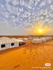 a group of tents in the desert with the sunset at Merzouga Infinity Dunes Camp in Merzouga