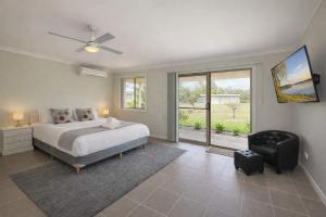a bedroom with a bed and a chair and a window at Marignano Homestead in Broke +17 photos