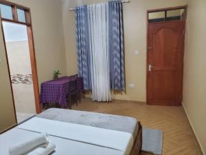 a room with a bed and a table and a door at Shilling Stays in Msaranga