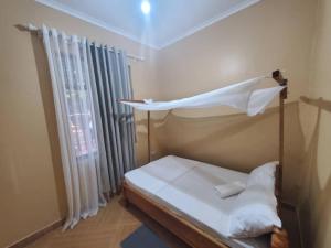 a bedroom with a bed and a window with curtains at Shilling Stays in Msaranga