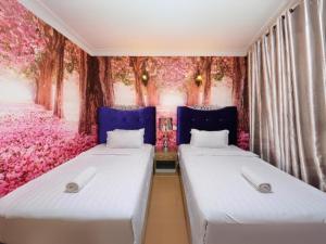 two beds in a room with pink flowers at Seeds Hotel Shah Alam Seksyen 7 I-City in Shah Alam