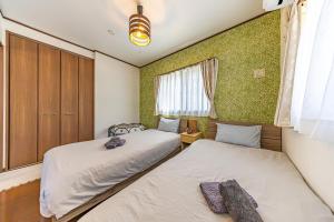 two beds in a room with green wallpaper at Unbi Stay in Nakijin