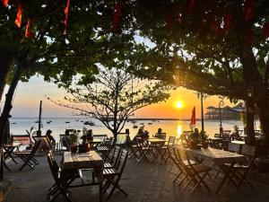 people sitting at tables on the beach at sunset at Hai Long homestay in Hoi An