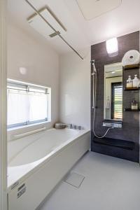 a white bathroom with a tub and a window at Unbi Stay in Nakijin +77 photos
