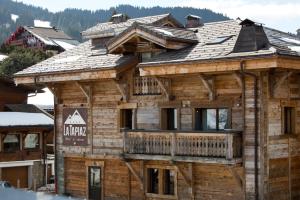 Chalet-Hôtel La Marmotte, La Tapiaz & SPA, The Originals Relais (Hotel-Chalet de Tradition) في لي جيه: كابينة خشبية مع شرفة في الجبال