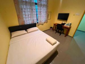 a bedroom with a bed and a desk with a television at Kemas Homestay in Johor Bahru +3 photos