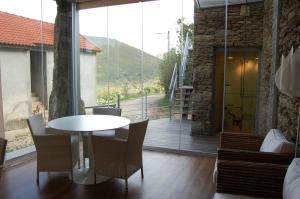 a table and chairs in a room with a large window at Quinta dos Castanheiros - Turismo Rural in Negreda