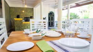 a wooden table with white plates and dishes on it at La Roche Hotel Sigiriya in Sigiriya