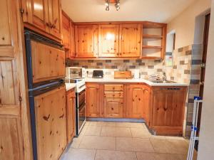 a kitchen with wooden cabinets and white appliances at Ghyll Bank Bungalow in Staveley +15 photos