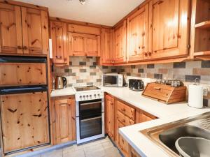 a kitchen with wooden cabinets and a sink at Ghyll Bank Bungalow in Staveley