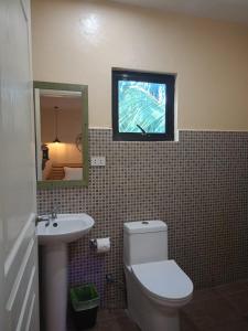 a bathroom with a toilet and a sink and a mirror at Datoni Italian Restaurant in Tabigue