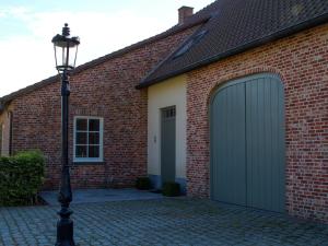 uma casa de tijolos com uma garagem com uma porta de garagem verde em This spacious holiday home in the smallest details em Peer