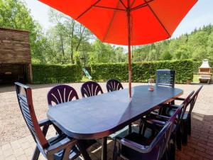 a blue table with a red umbrella and chairs at Modern Holiday Home in Waimes near Lake in Waimes