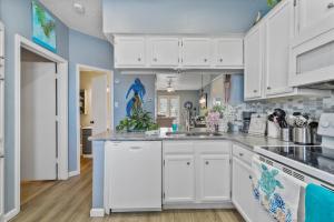 a kitchen with white cabinets and blue walls at Island Palms - 2 min walk to the Beach in Corpus Christi