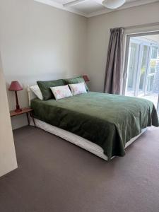 a bedroom with a large green bed with a window at The King's Rest in Matamata